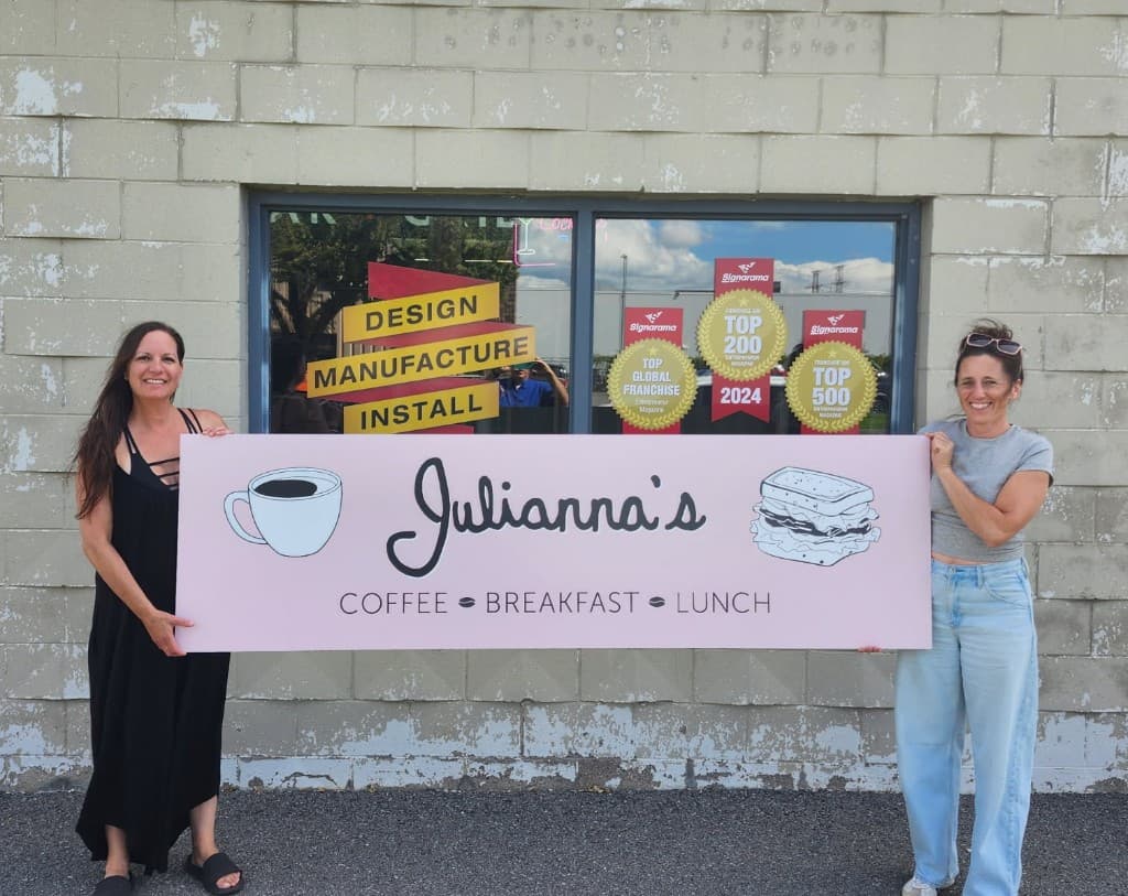 April and Kristine holding the Julianna’s Coffee Breakfast Lunch sign in front of the shop